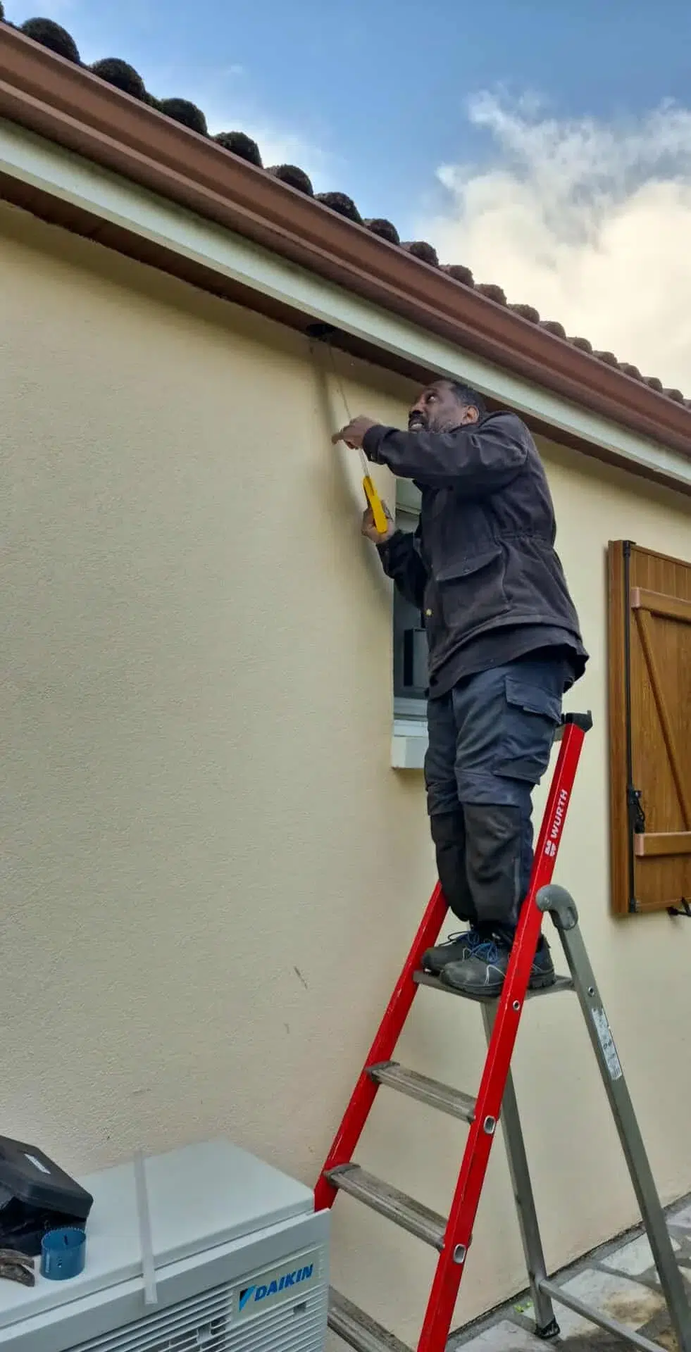 Homme sur une échelle réparant un mur